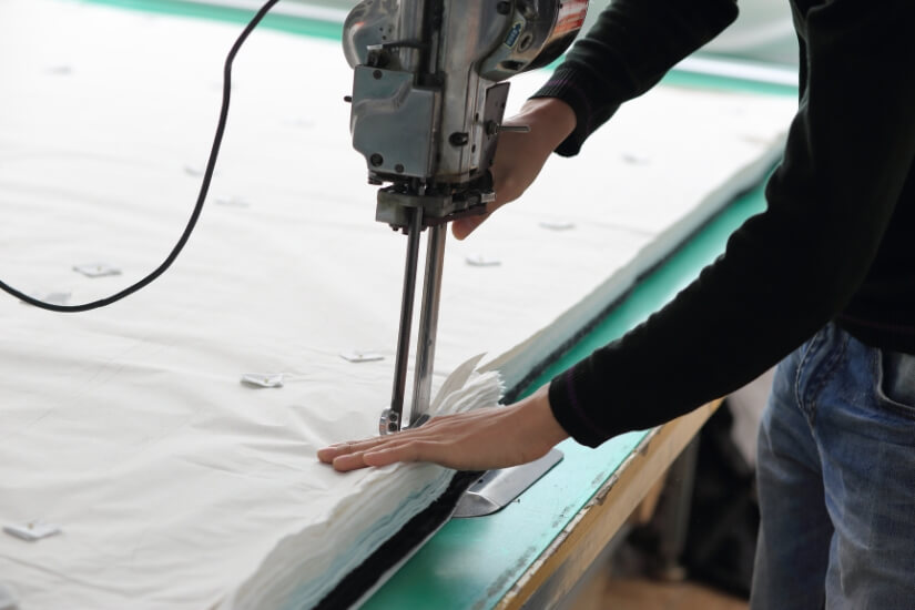 a-person-cutting-number-of-layers-of-fabric-in-industry-setting-machine (1)